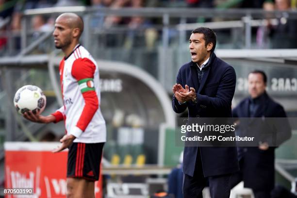 Feyenoord's Moroccan midfielder Karim El Ahmadi holds the ball as Dutch coach Giovanni van Bronkhorst reacts during the Dutch Eredivisie football...