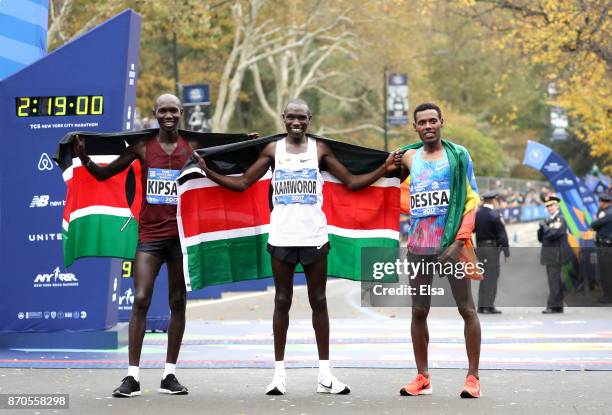 Geoffrey Kamworor of Kenya celebrates winning the Professional Men's Division with Wilson Kipsang of Kenya and Lelisa Desisa of Ethiopia during the...