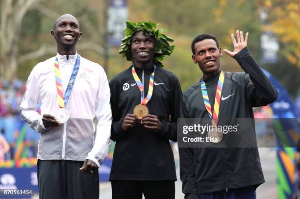 Geoffrey Kamworor of Kenya celebrates winning the Professional Men's Division with Wilson Kipsang of Kenya and Lelisa Desisa of Ethiopia during the...