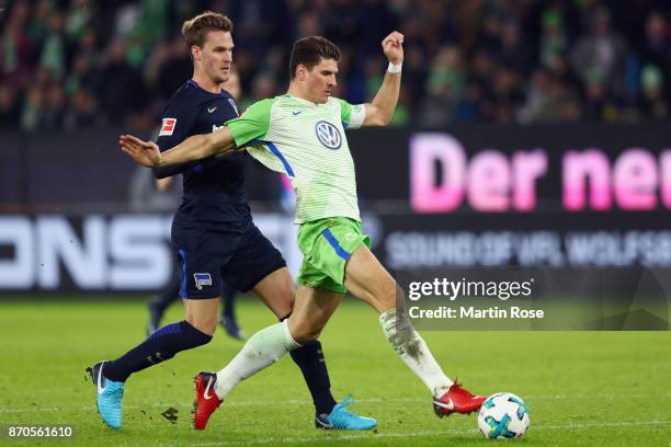 Mario Gomez of Wolfsburg scores his team's second goal under pressure from Sebastian Langkamp of Berlin during the Bundesliga match between VfL...