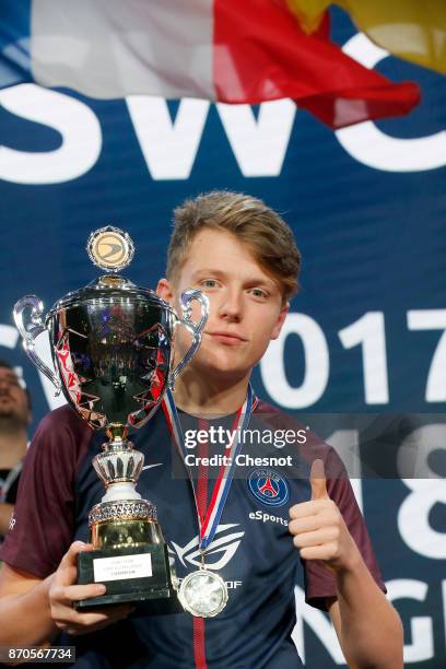 French E-Sports player Lucas Cuillerier, gamertag 'DaXe' of the Paris Saint-Germain eSports team poses with the trophy after his victory in the final...
