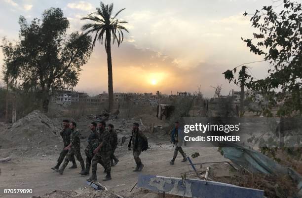 Syrian government forces walk through a road in a northeastern district of Deir Ezzor on November 5 after retaking the city from Islamic State group...