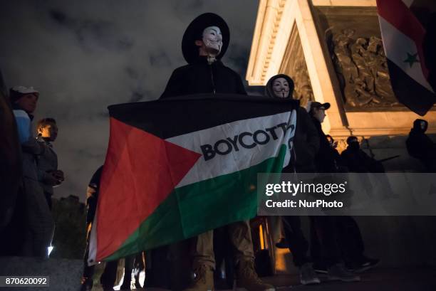 Protester wears the iconic Guy Fawkes mask and waves a Palestine flag in Trafalgar Square during the anti-capitalist 'Million Masks March', organised...