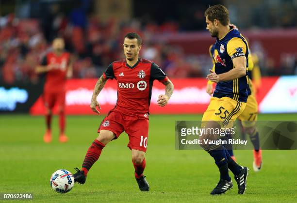 Sebastian Giovinco of Toronto FC dribbles the ball as Damien Perrinelle of New York Red Bulls defends during the first half of the MLS Eastern...