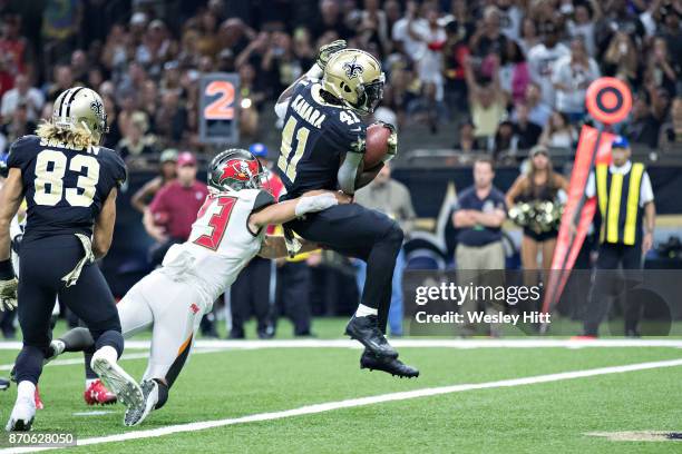 Alvin Kamara of the New Orleans Saints runs the ball in for a touchdown past Chris Conte of the Tampa Bay Buccaneers at Mercedes-Benz Superdome on...