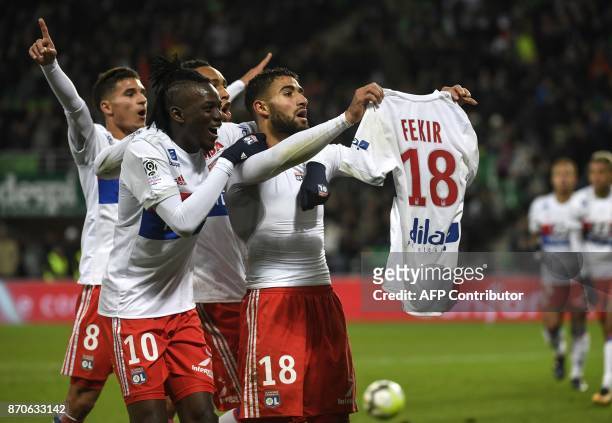 Lyon's French midfielder Nabil Fekir shows his shirt as is congratulated by team mates after scoring during the French L1 football match between AS...