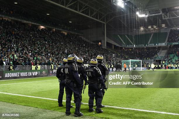 French riot police stand on the sideline of the pitch after fans interrupted the match during the French L1 football match between AS Saint-Etienne...