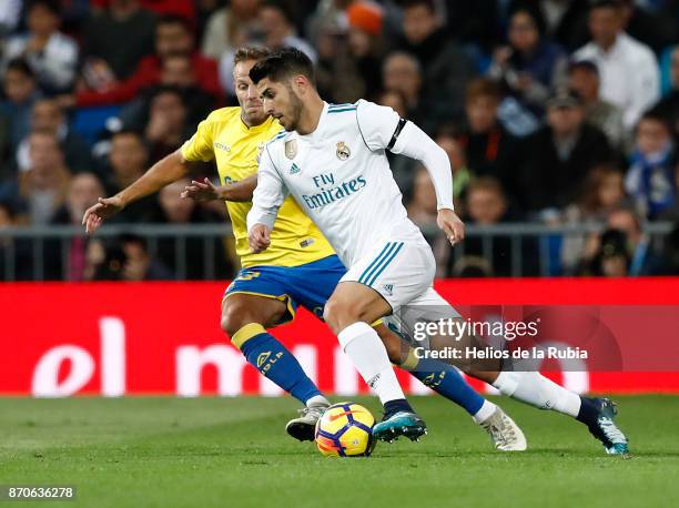 Marco Asensio of Real Madrid and Mauricio Lemos of Las Palmas compete for the ball during the La Liga match between Real Madrid and Las Palmas at...