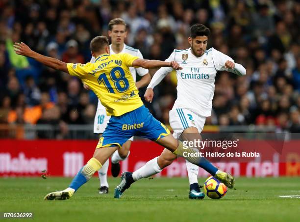 Marco Asensio of Real Madrid and Javi Castellano of Las Palmas compete for the ball during the La Liga match between Real Madrid and Las Palmas at...