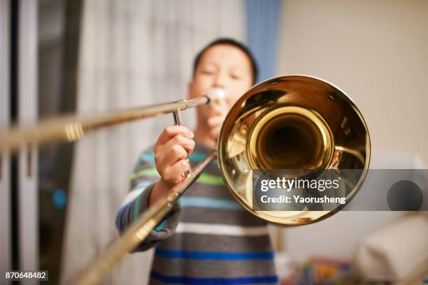 portrait of a boy playing the trombone - kids instruments stock-fotos und bilder