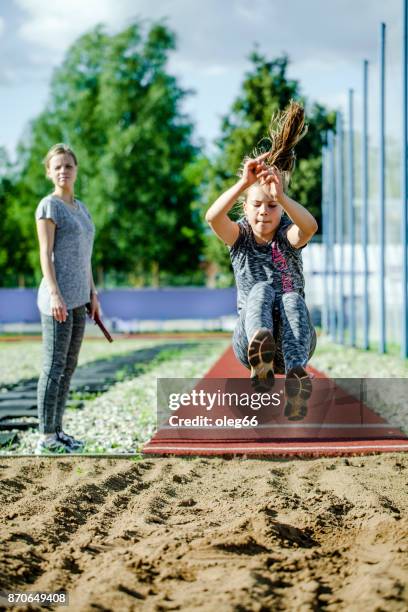 mädchen-teenager-züge im weitsprung - woman long jump stock-fotos und bilder