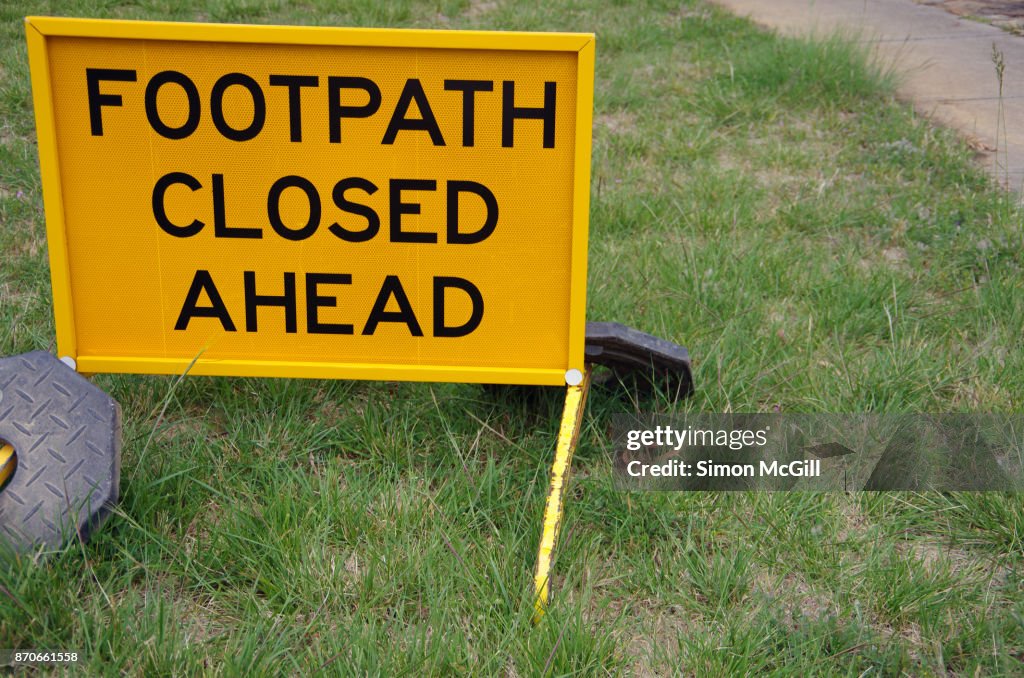 FOOTPATH CLOSED AHEAD sign beside a concrete footpath