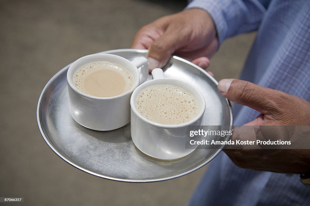 Man holding chai tea on a steel patter.