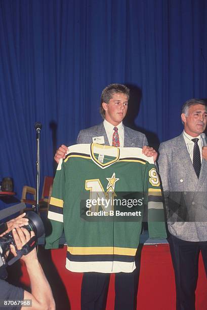 American ice hockey player Mike Modano poses with Lou Nanne, coach of the Minnesota North Stars, as they hold a North Stars jersey following Modano's...