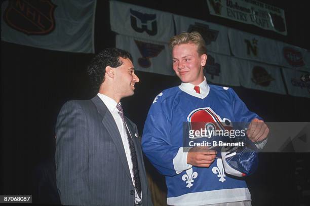 Swedish ice hockey player Mats Sundin wears a Quebec Nordiques jersey as he smiles at an unidentified man following his first round, first place...