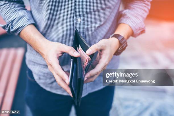 man standing holding black wallet full of money - wallet stock-fotos und bilder