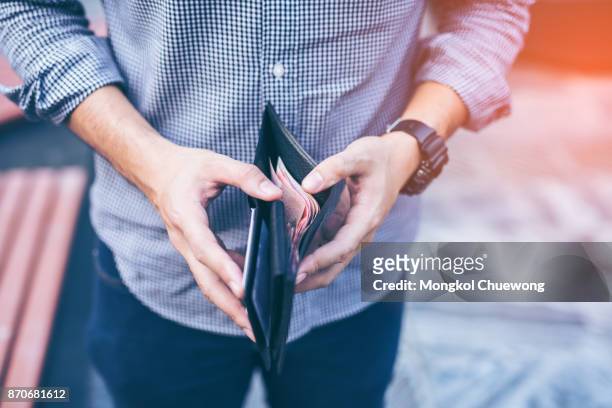 man standing holding black wallet full of money - wallet stockfoto's en -beelden