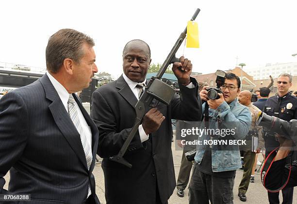 Los Angeles police department Deputy Chief Charles Beck looks on as Lt. Fred Booker displays a 12 gauge shotgun assault weapon called a Streetsweeper...