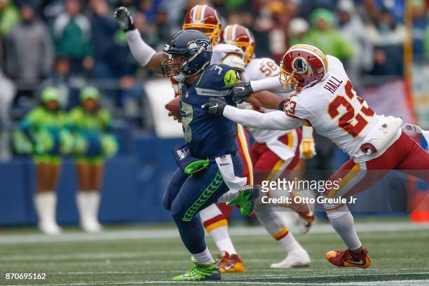 Quarterback Russell Wilson of the Seattle Seahawks rushes against safety DeAngelo Hall of the Washington Redskins at CenturyLink Field on November 5,...