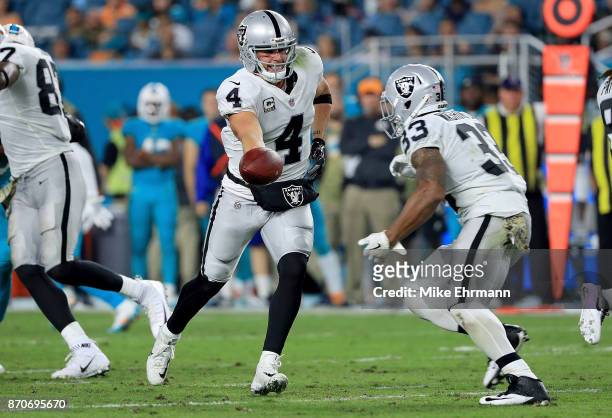Derek Carr hands off to DeAndre Washington of the Oakland Raiders during a game against the Miami Dolphins at Hard Rock Stadium on November 5, 2017...