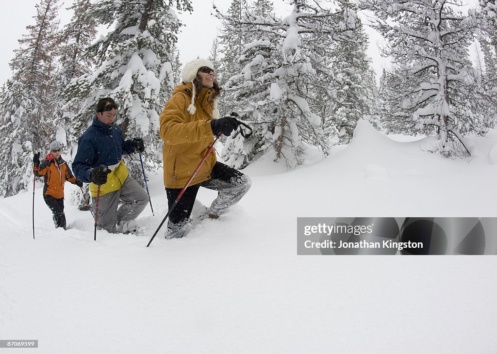 Side view of three people snowshoeing in the woods in deep powder in Bend, Oregon.