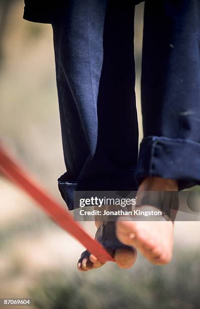 close up of a man's bare feet balancing on a tight rope or slackline in the california desert. - man in tight pants stock pictures, royalty-free photos & images