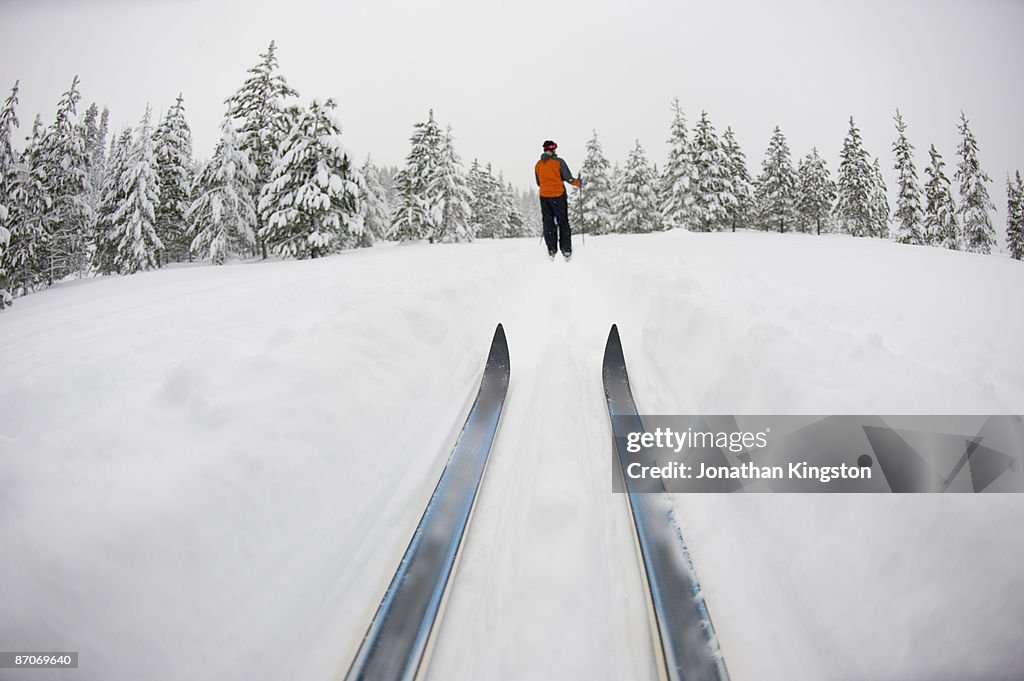 Low angle view of cross country ski tips and one young woman Nordic skiing on a cross country trial in the snow in Bend, Oregon.