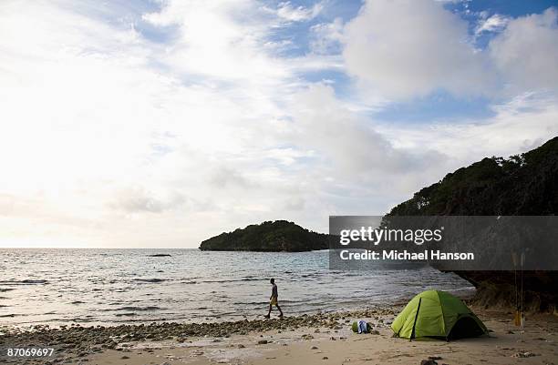 a man walks next to a green tent on an island in the lau group in fiji, south pacific. - michael lau 個照片及圖片檔