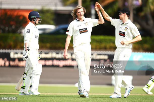 David Moody of the Warriors celebrates with Jason Behrendorff of the Warriors after taking the wicket of Nic Maddinson of the Blues during day three...
