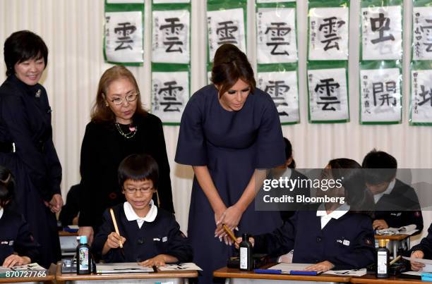 First Lady Melania Trump, center, and Akie Abe, wife of Japan's Prime Minister Shinzo Abe, left, interacts with students in a calligraphy class...