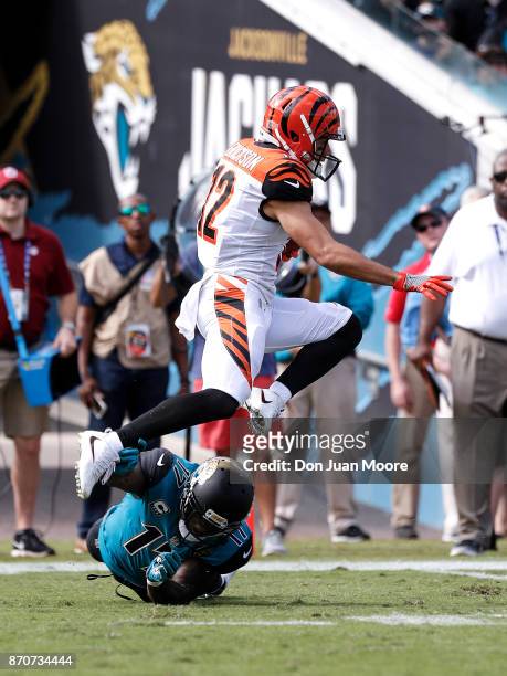 Wide Receiver Alex Erickson of the Cincinnati Bengals leaps over Wide Receiver Arrelious Benn of the Jacksonville Jaguars on a kick-off return during...