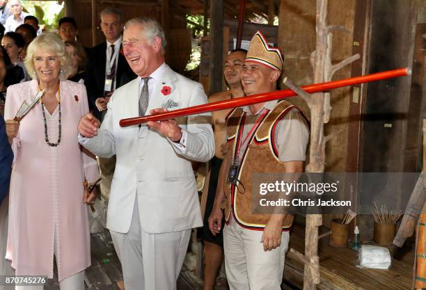 Prince Charles, Prince of Wales laughs after blowing a dart, as Camilla, Duchess of Cornwall looks on, during a visit to the Sarawak Cultural...