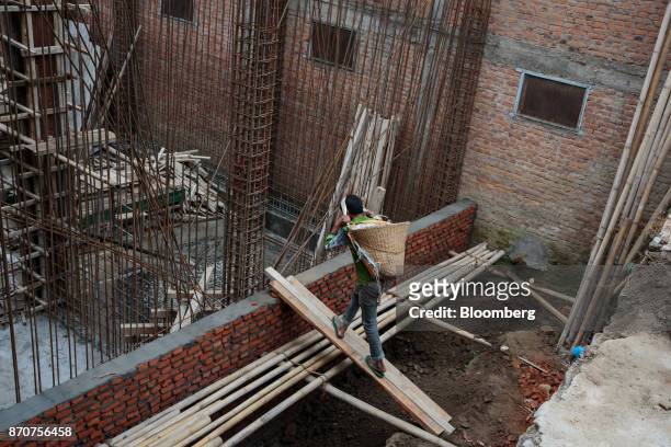 Worker carrying a basket of cement on his back walks up a ramp to a residential building under construction in Kathmandu, Nepal, on Wednesday, Nov....