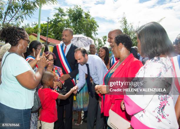 France's Prime Minister Edouard Philippe , flanked by mayor of Les Abymes Eric Jalton speaks with a child in Les Abymes on the French Caribbean...