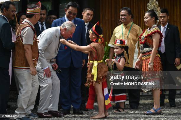 Britain's Prince Charles is greeted by a boy in Bidayuh traditional costume after arriving at the Sarawak Cultural Village in Santubong, outside...