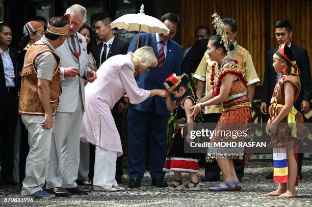 Camilla, Duchess of Cornwall shakes hands with a girl in Bidayuh traditional costume after arriving at the Sarawak Cultural Village in Santubong,...