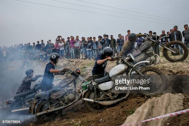 Minsk motorcyclists try to get over the dirt slope at an off-road race on November 5, 2017 in Hanoi, Vietnam. A new generation of Vietnamese have...