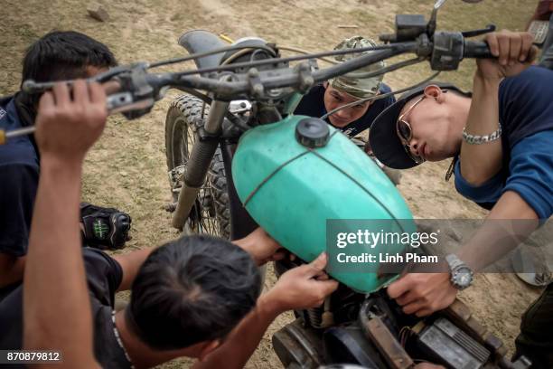 Minsk motorcycle enthusiasts help each others fine-tuning and fixing their vehicles before the off-road race on November 5, 2017 in Hanoi, Vietnam. A...