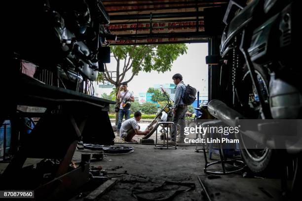 Minsk motorcycle enthusiast repairs his tire while on the way to the off-road race on November 5, 2017 in Hanoi, Vietnam. A new generation of...