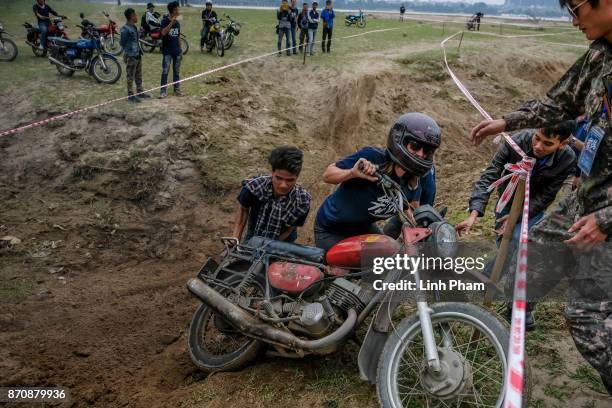 Female male Minsk motorcyclist crashes while trying to get over the dirt slope at an off-road race on November 5, 2017 in Hanoi, Vietnam. A new...