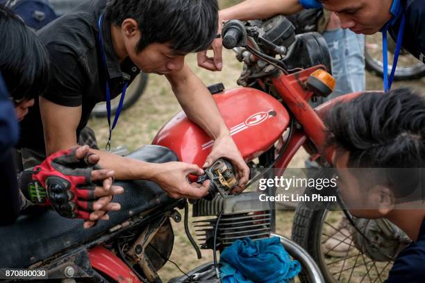 Minsk motorcycle enthusiasts help each others fine-tuning and fixing their vehicles before the off-road race on November 5, 2017 in Hanoi, Vietnam. A...