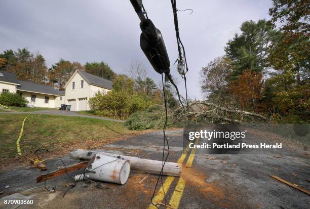 Utility pole with a transformer attached still lies in the middle of Flying Point Road in Freeport, under wires weighted down by trees that block the...