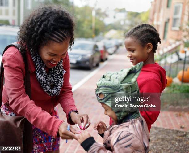 Kim Janey, left, who is running for Boston's District 7 City Council seat, hands out stickers while campaigning in Boston on Nov. 4, 2017.