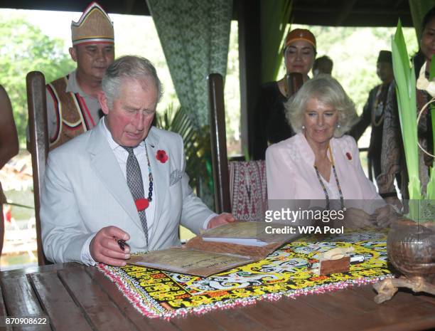 Prince Charles, Prince of Wales and Camilla, Duchess of Cornwall sign the guestbook during a visit to Sarawak Cultural Village on November 6, 2017 in...