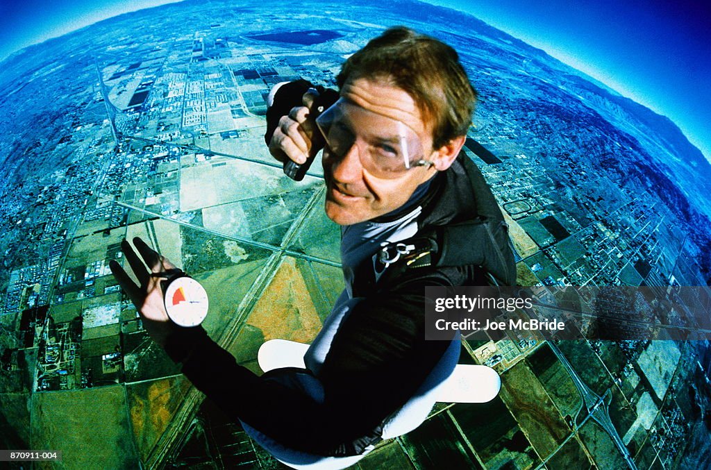 Skyboarding, man using mobile phone at altitude, portrait (wide angle)