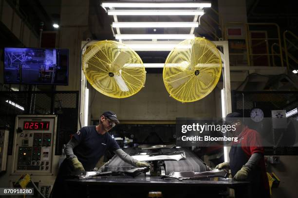 Workers collect metal parts while exiting a conveyor belt at the stamping plant of the Nissan Motor Co. Manufacturing facility in Smyrna, Tennessee,...