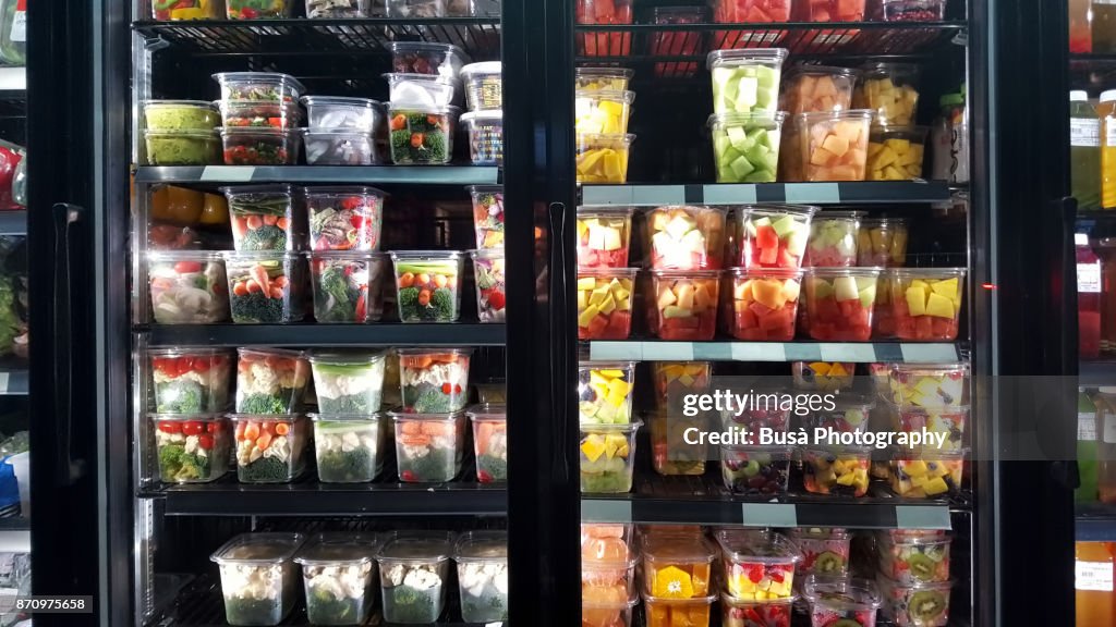 Healthy cut fruit and vegetables on display in store window of a grocery store in the East Village, New York City