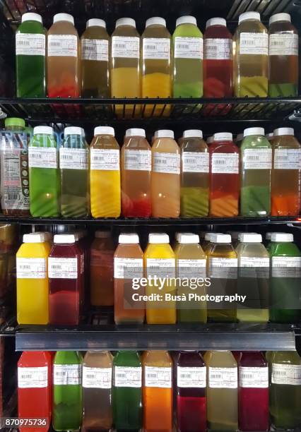 healthy fruit and vegetable juices on display in store window of a grocery store in the east village, new york city - grocery store window stock pictures, royalty-free photos & images