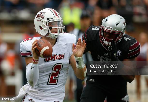 Ross Comis of the Massachusetts Minutemen throws a pass while under pressure from Gerri Green of the Mississippi State Bulldogs during the first half...