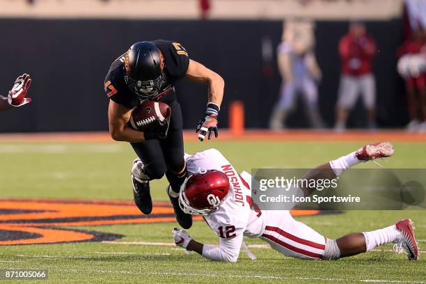 Oklahoma Sooners DB Will Johnson bringing down Oklahoma State Cowboys WR, Dillon Stoner during a college football game between the Oklahoma Sooners...